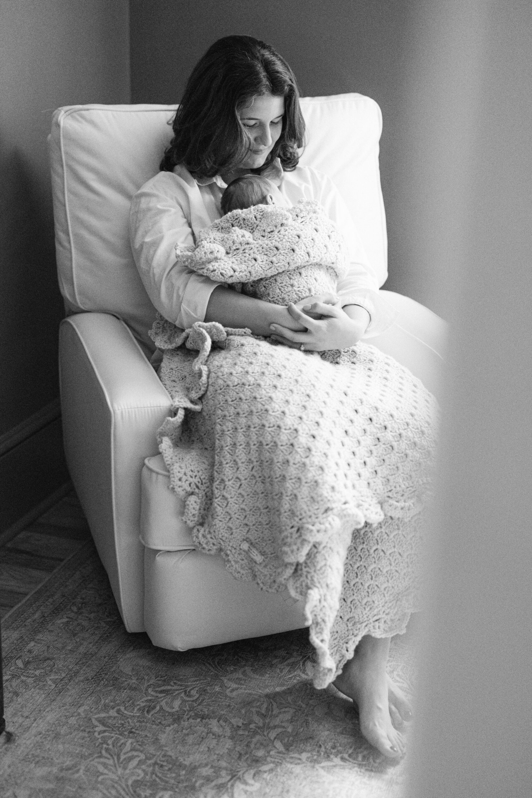 mom rocking newborn in chair in newborn session with Caroline Eidson