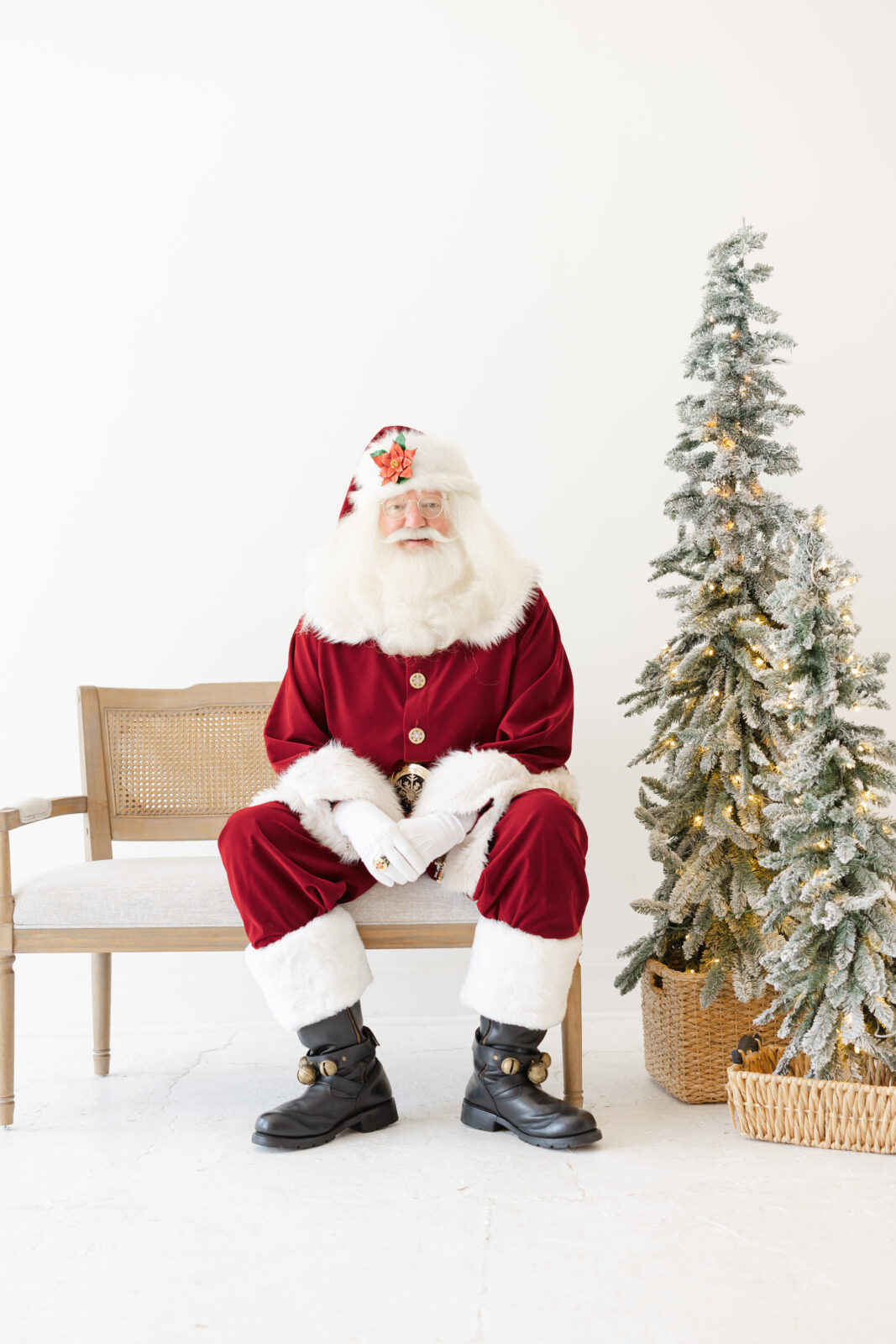 Santa sitting on a bench next to a Christmas tree for pictures with Santa