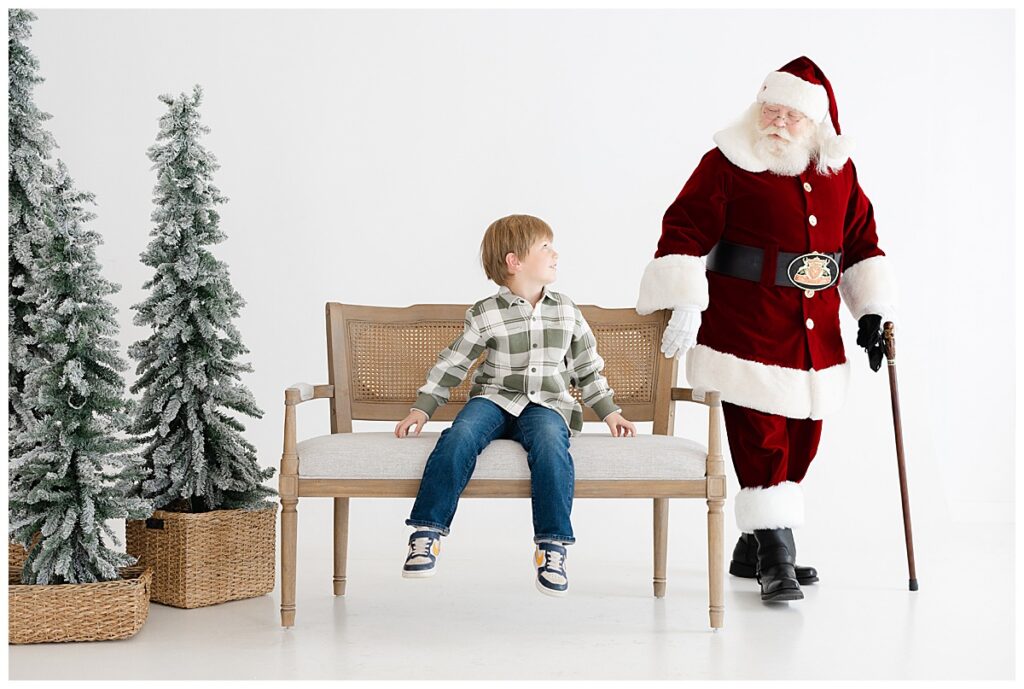 Santa talking with a young boy beside a Christmas tree during Tulsa Santa mini sessions